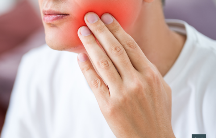 Young male holding his jaw in a sore spot